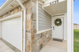 Doorway to property featuring stone siding and a garage