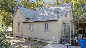 View of side of property featuring a shingled roof and stucco siding