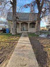 View of front facade featuring covered porch, a shingled roof, and stucco siding