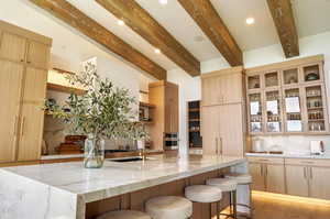 Kitchen featuring light stone counters, recessed lighting, light brown cabinetry, beamed ceiling, and decorative backsplash