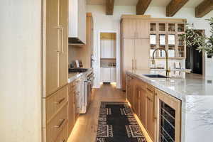 Kitchen featuring glass insert cabinets, light stone countertops, light brown cabinets, range with two ovens, and light wood finished floors