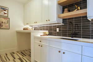 Kitchen with open shelves, white cabinets, tasteful backsplash, and light floors