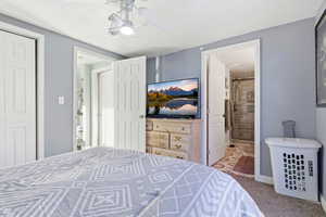Carpeted bedroom featuring a ceiling fan, a closet, and connected bathroom