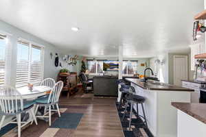 Kitchen featuring dark countertops, a breakfast bar, white cabinets, and dark wood-type flooring