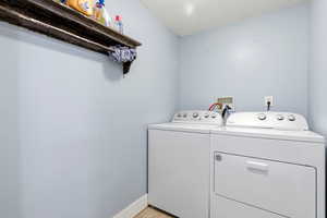 Laundry room with independent washer and dryer and light wood-style flooring
