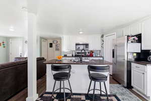 Kitchen featuring white cabinets, a kitchen island with sink, a kitchen bar, and recessed lighting