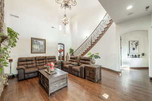 Living area with arched walkways, dark wood finished floors, stairs, and a towering ceiling