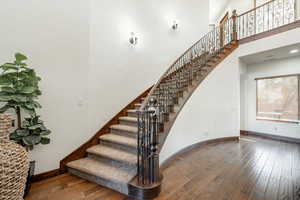 Stairway featuring a high ceiling, arched walkways, and wood-type flooring