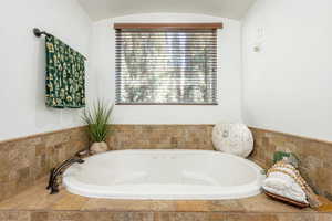 Full bath featuring a garden tub and lofted ceiling