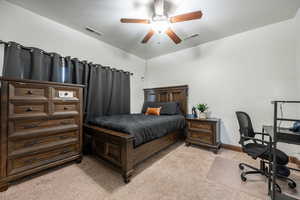 Bedroom featuring an office area, light colored carpet, and a ceiling fan