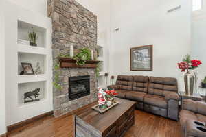 Living room featuring built in features, a high ceiling, dark wood-style floors, and a fireplace