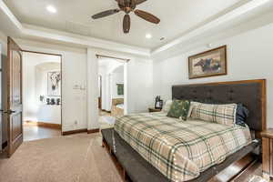 Carpeted bedroom with arched walkways, a raised ceiling, connected bathroom, recessed lighting, and a ceiling fan