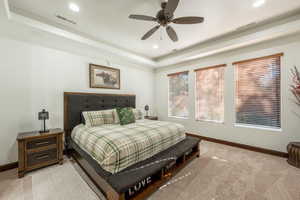 Carpeted bedroom with a tray ceiling, a ceiling fan, and recessed lighting