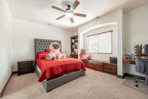Bedroom with a ceiling fan, an office area, and light colored carpet