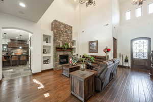 Living room with arched walkways, built in features, a towering ceiling, dark wood finished floors, and recessed lighting