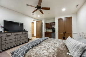 Bedroom with a closet, light carpet, ceiling fan, stainless steel refrigerator, and recessed lighting