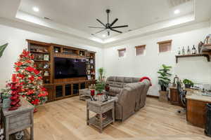 Living area with a desk, a raised ceiling, light wood-style flooring, and recessed lighting