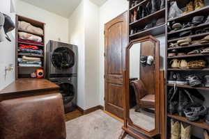 Laundry area featuring stacked washing machine and dryer and baseboards