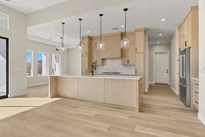 Kitchen featuring light brown cabinets, pendant lighting, high end fridge, backsplash, and light wood-type flooring