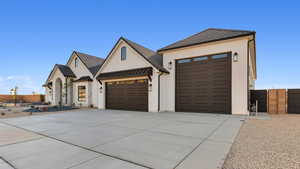View of front of home with an attached garage, a standing seam roof, a metal roof, driveway, and stucco siding