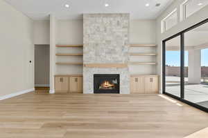 Unfurnished living room with a fireplace, built in features, recessed lighting, and light wood finished floors