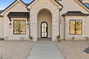Doorway to property with stone siding, a standing seam roof, and a metal roof