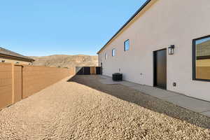 View of side of home featuring a mountain view, a fenced backyard, stucco siding, and a patio area