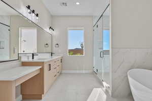 Full bath featuring vanity, a soaking tub, a marble finish shower, tile walls, and light tile patterned floors