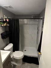 Full bathroom with a stall shower, vanity, a textured ceiling, and light tile patterned floors