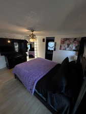 Bedroom with a textured ceiling, ceiling fan, and wood finished floors