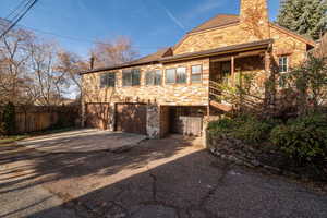 View of front of house featuring brick siding, a chimney, driveway, and a garage