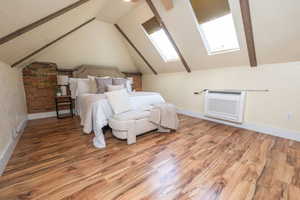 Bedroom featuring wood finished floors, a skylight, and vaulted ceiling