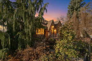 Tudor-style house featuring stone siding, a balcony, and roof with shingles