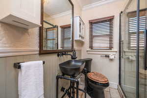 Full bath featuring a textured wall, crown molding, a shower stall, a textured ceiling, and a wainscoted wall
