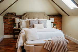 Bedroom with lofted ceiling, a textured wall, a skylight, and wood finished floors