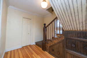 Staircase with hardwood / wood-style flooring, ornamental molding, a textured ceiling, and a textured wall