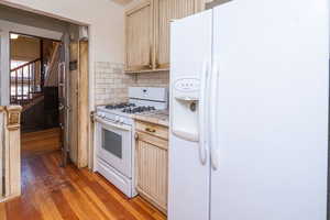 Kitchen featuring white appliances, tile counters, light wood-type flooring, decorative backsplash, and crown molding