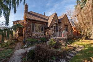 Tudor house with stone siding, a chimney, and a shingled roof