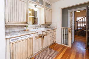 Kitchen featuring tile counters, glass insert cabinets, dishwasher, light wood-style floors, and light brown cabinetry