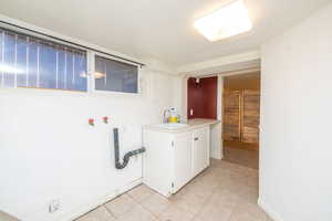 Laundry area with light tile patterned floors, washer hookup, and cabinet space