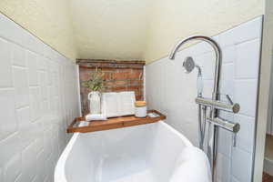 Bathroom view of a freestanding bath and tile walls