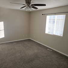 Spare room featuring dark carpet and baseboards