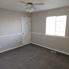 Empty room with dark colored carpet and a ceiling fan