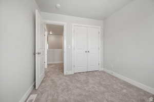 Unfurnished bedroom with light carpet and a closet