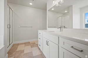 Bathroom featuring vanity, a stall shower, recessed lighting, and stone finish floors