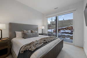 Bedroom with light colored carpet, access to exterior, and vaulted ceiling