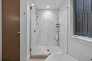 Bathroom featuring a shower stall, a freestanding tub, and recessed lighting