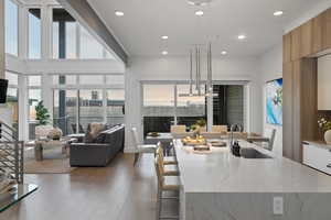 Kitchen with light stone countertops, modern cabinets, hanging light fixtures, wood finished floors, and open floor plan