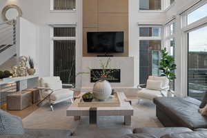 Living area with wood finished floors, a fireplace, a high ceiling, and stairs