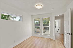 Unfurnished room with a textured ceiling and light wood-style floors